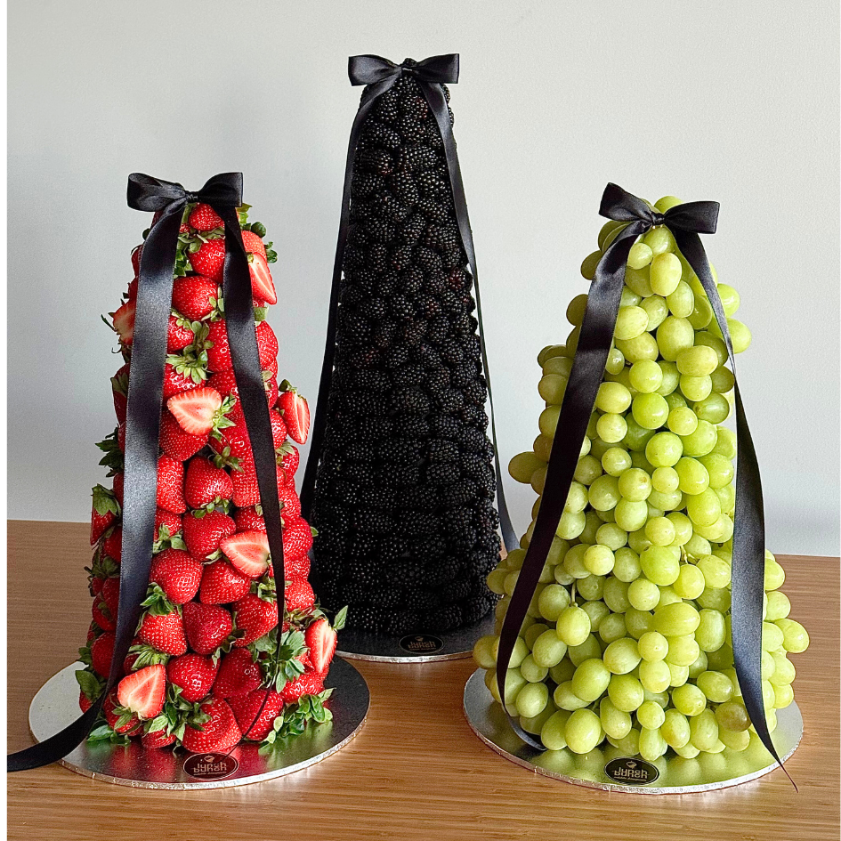 Three fresh fruit towers featuring a blackberry tower in the centre, with strawberry and grape towers on either side, styled for event dessert tables.