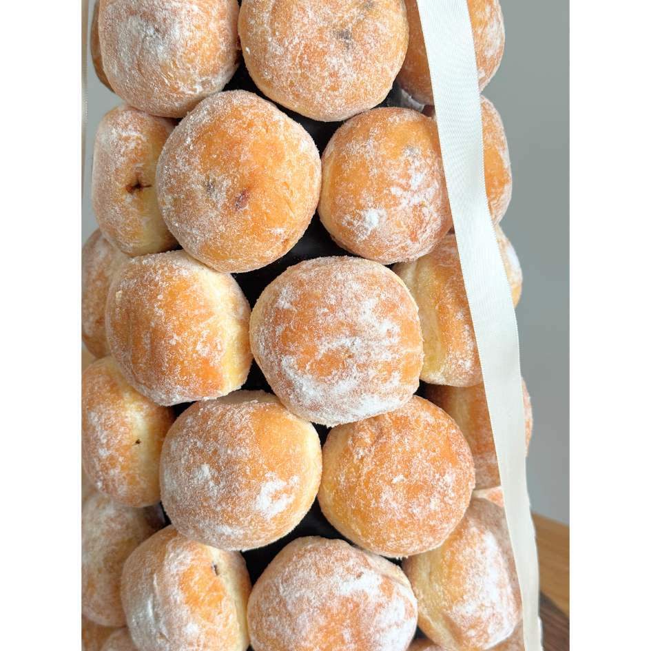 Close-up of sugar-dusted Nutella and salted caramel bombolini donuts on a rustic donut tower for event dessert tables