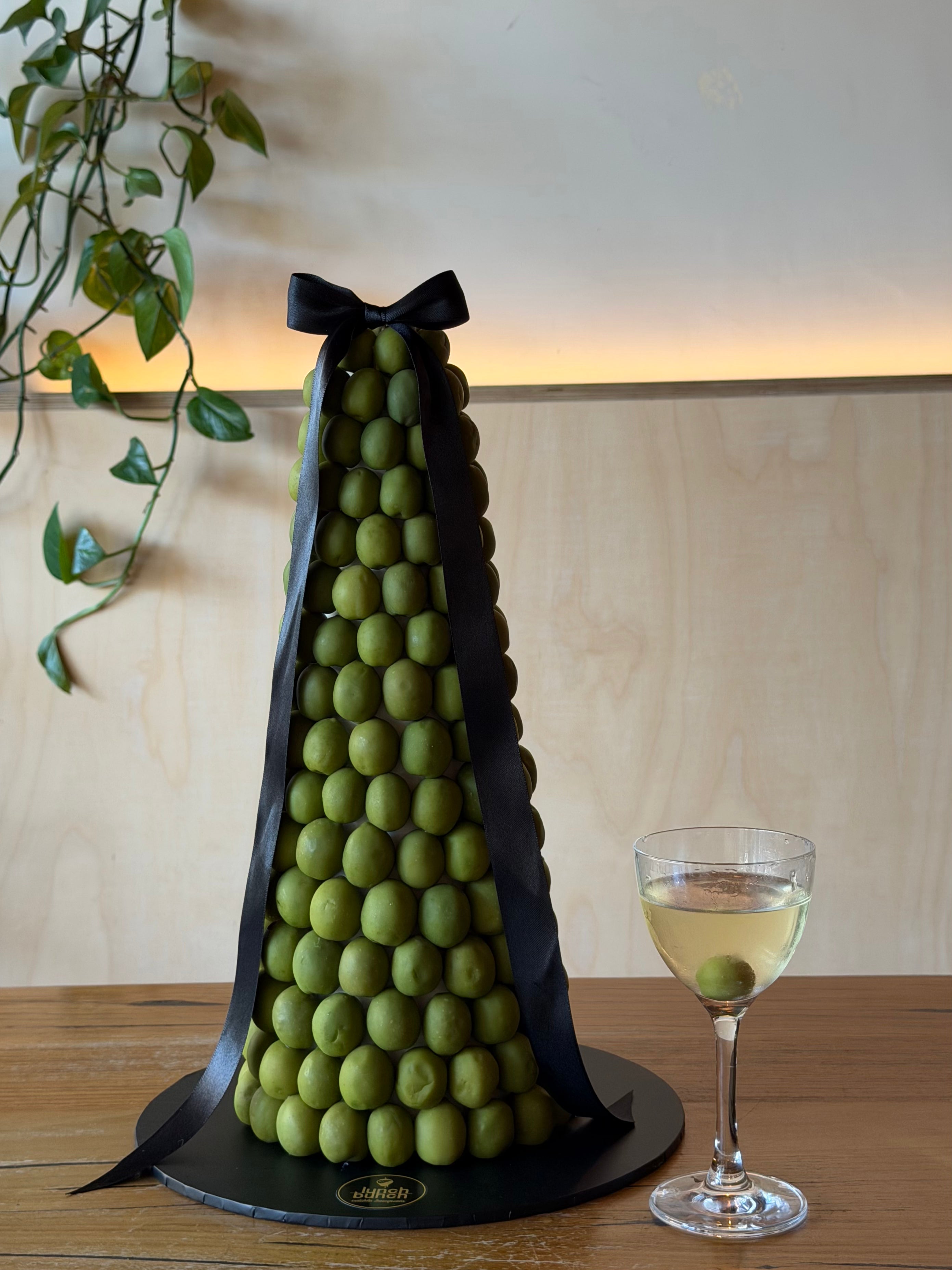 a tower of green olives next to a martini glass