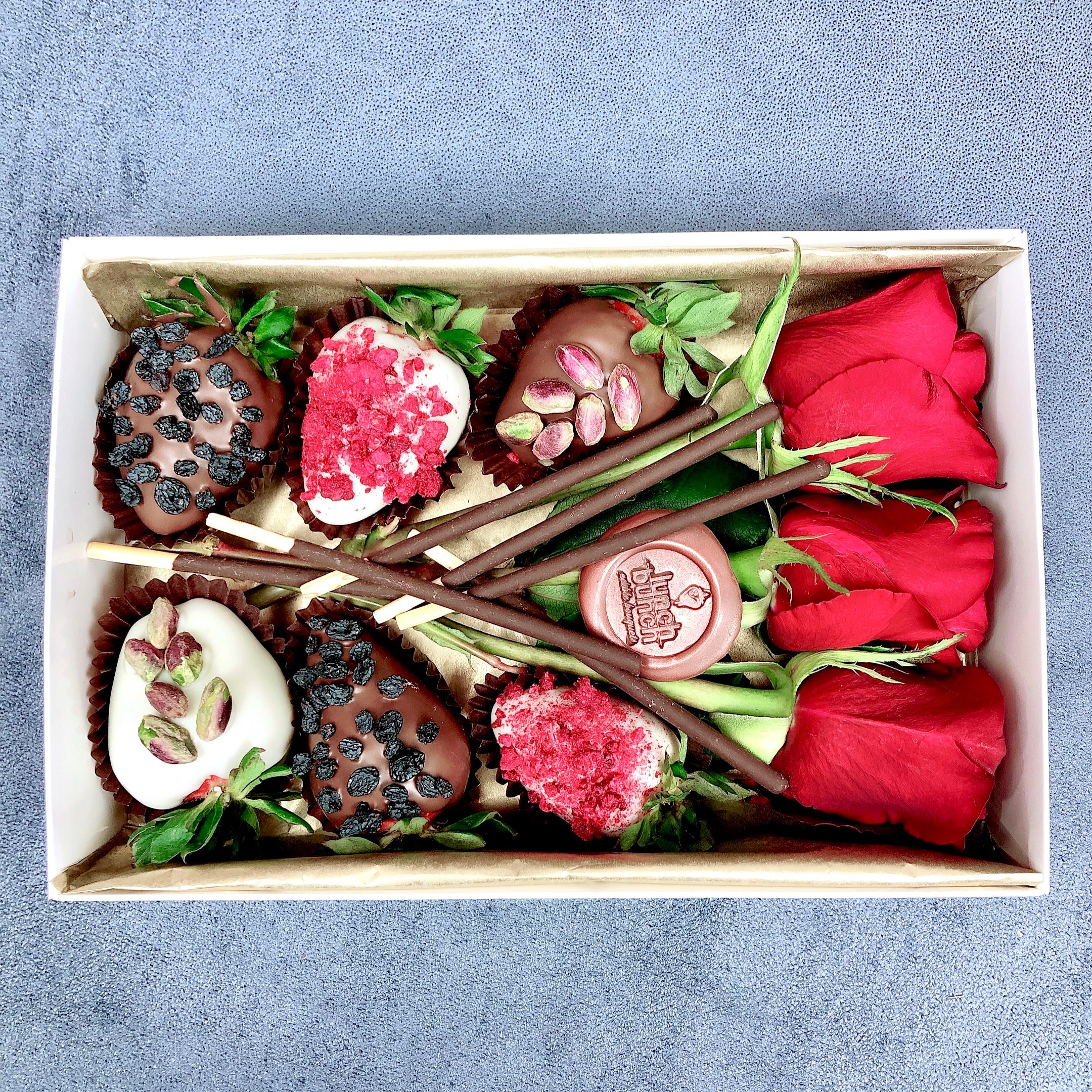 Red roses and chocolate covered strawberries give the box