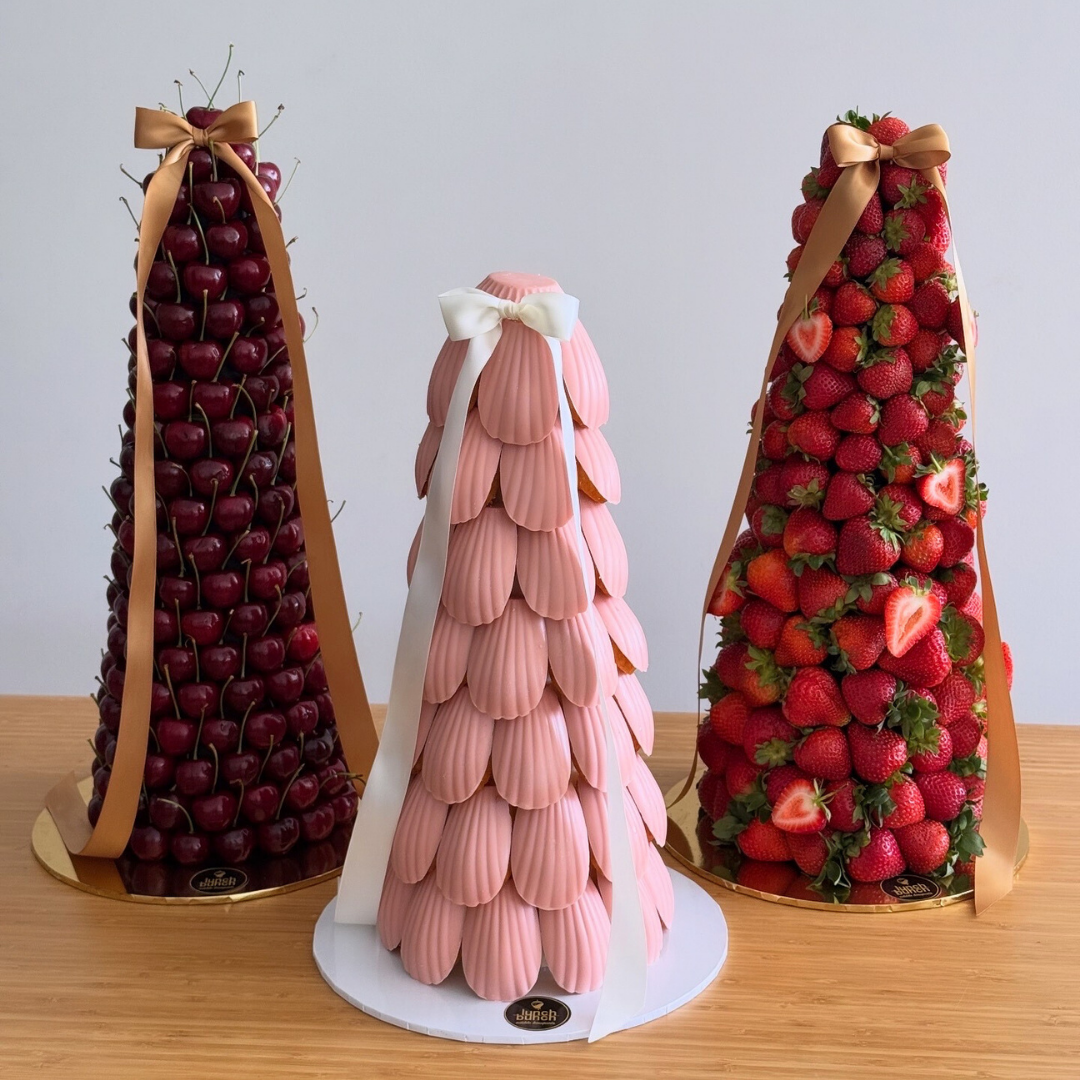 Pink madeleine cake tower displayed on an event dessert table, ideal for baby showers, birthdays and celebrations.