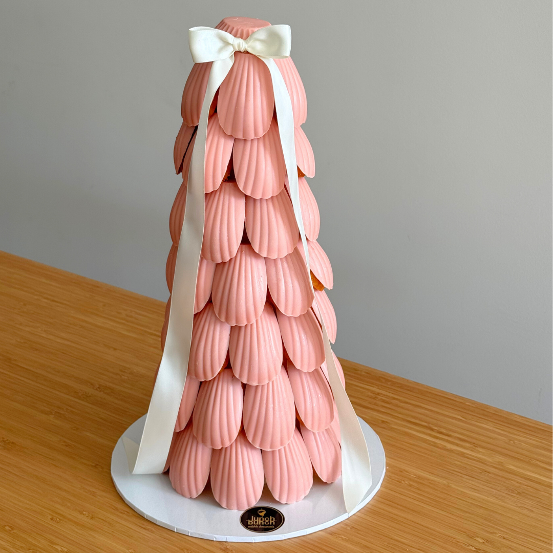 pink chocolate glazed madeleine cakes arranged on a dessert tower for baby shower and birthday events.