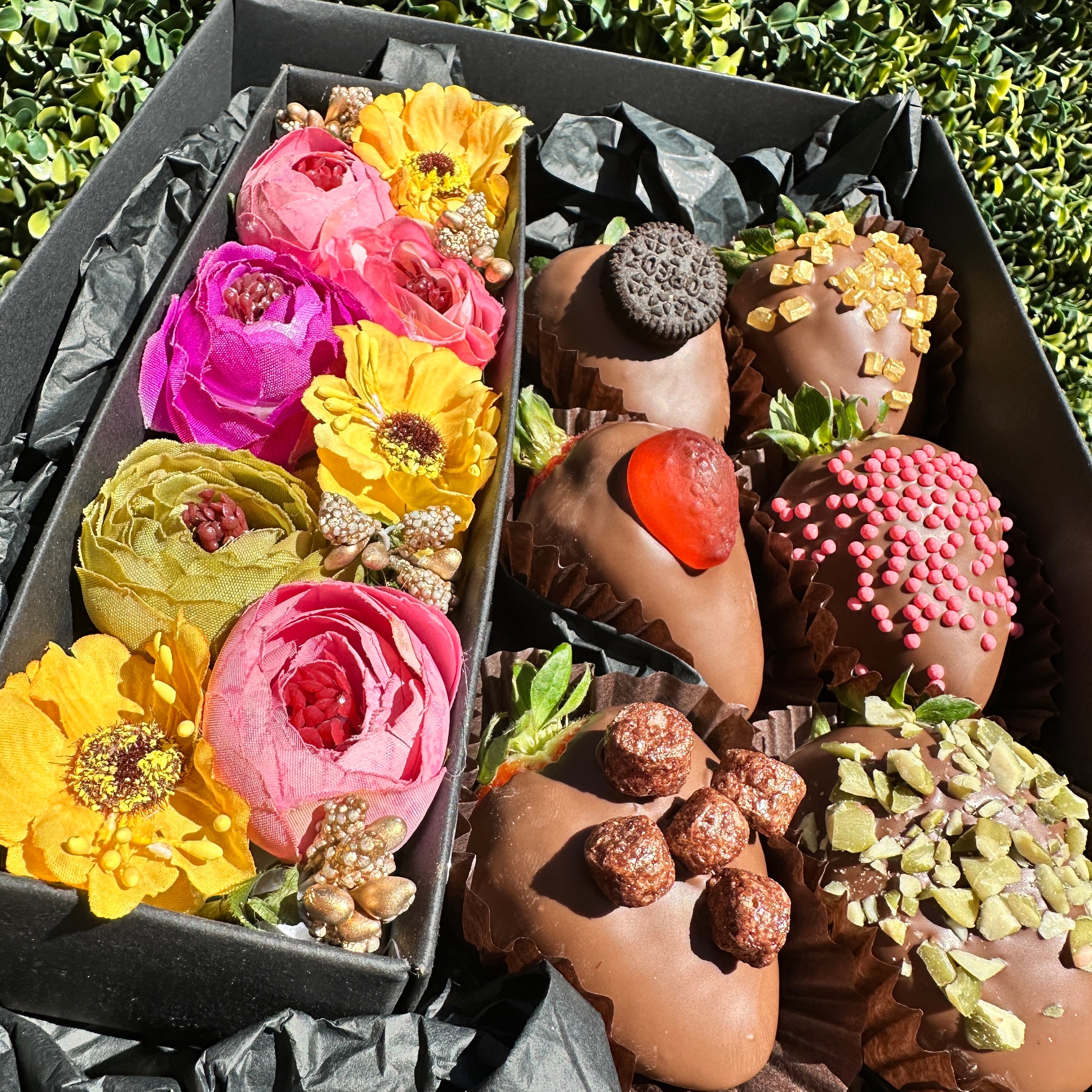 Chocolate strawberries arranged beside a petite silk flower gift box