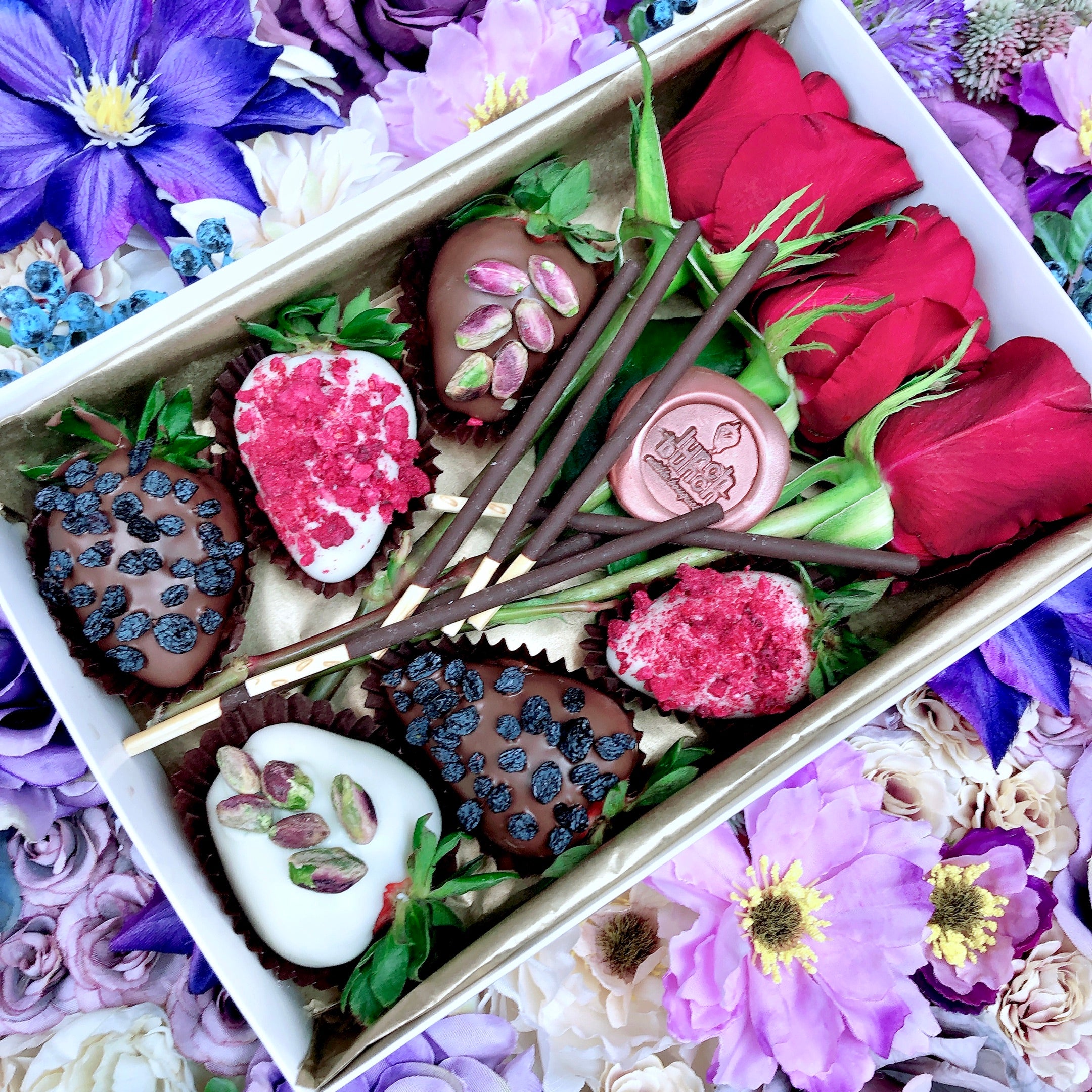 Chocolate decorated strawberries and red roses in a gift box