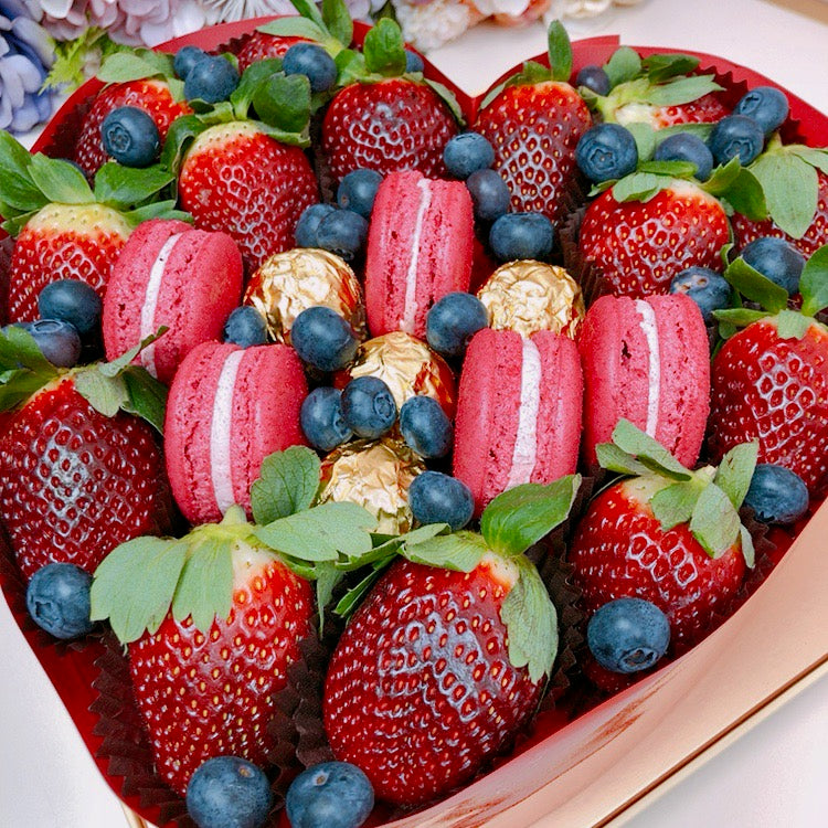 Fresh local strawberries and macaroons in love heart shape gift box with blueberries